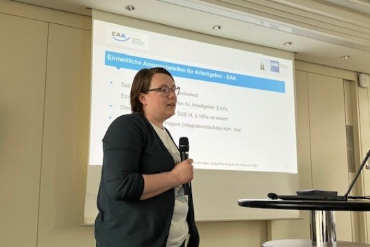 Das Bild zeigt eine Referentin der EAA vor einer Power Point Präsentation zu den EAA
