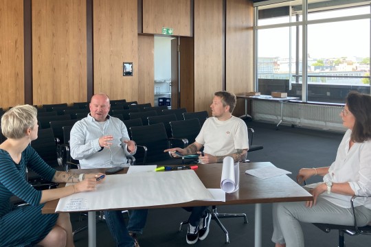 Das Bild zeigt vier EAA-Fachberatenden, die gemeinsam an einem Tisch sitzen und eine Kleingruppenarbeit machen.