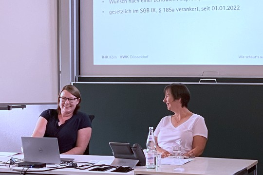 Auf dem Foto sind zwei EAA-Fachberaterinnen zu sehen, die vor einer PowerPoint Präsentation sitzen.