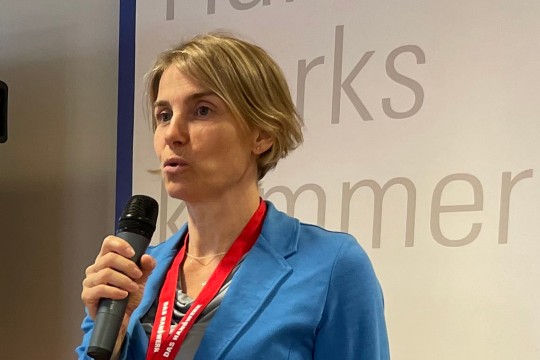 Auf dem Bild ist eine Person zu sehen, die in der Decke bohrt und dabei ein Exoskelett auf dem Rücken trägt.