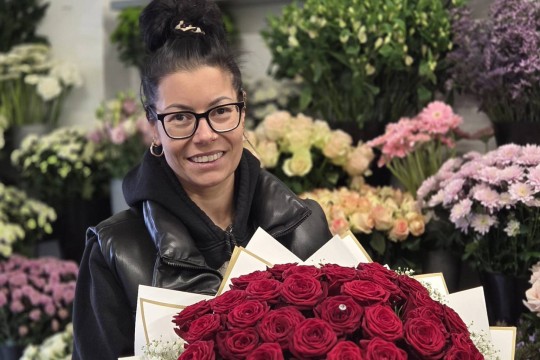 Das Bild zeigt die Besitzerin eines Blumenladen Sabrina Herbeck mit einem großen Strauß Rosen in der Hand.