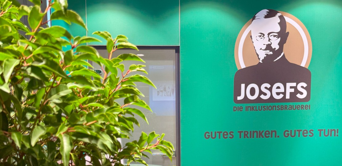 Das Bild zeigt das Logo der Inklusionsbrauerei Josefs und den Dschungelstand.
