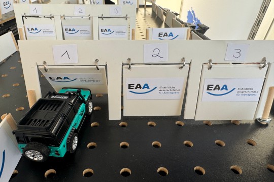 Auf dem Bild ist ein kleines ferngesteuertes Auto zu sehen, dass durch den EAA-Parcours fährt.