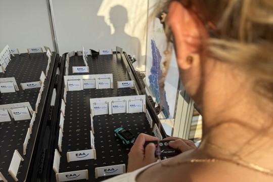 Auf dem Bild ist eine Frau zu sehen, die mit dem ferngesteuerten Auto durch den EAA-Parcours fährt.