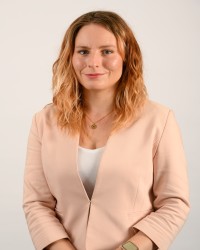 Portrait von Frau Esser: Frau Esser hat lange orange-blonde Locken und lächelt in die Kamera.